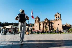Mochilero caminando hacia la Catedral del Cusco con mochila a cuestas, representando el turismo independiente y económico en 2025